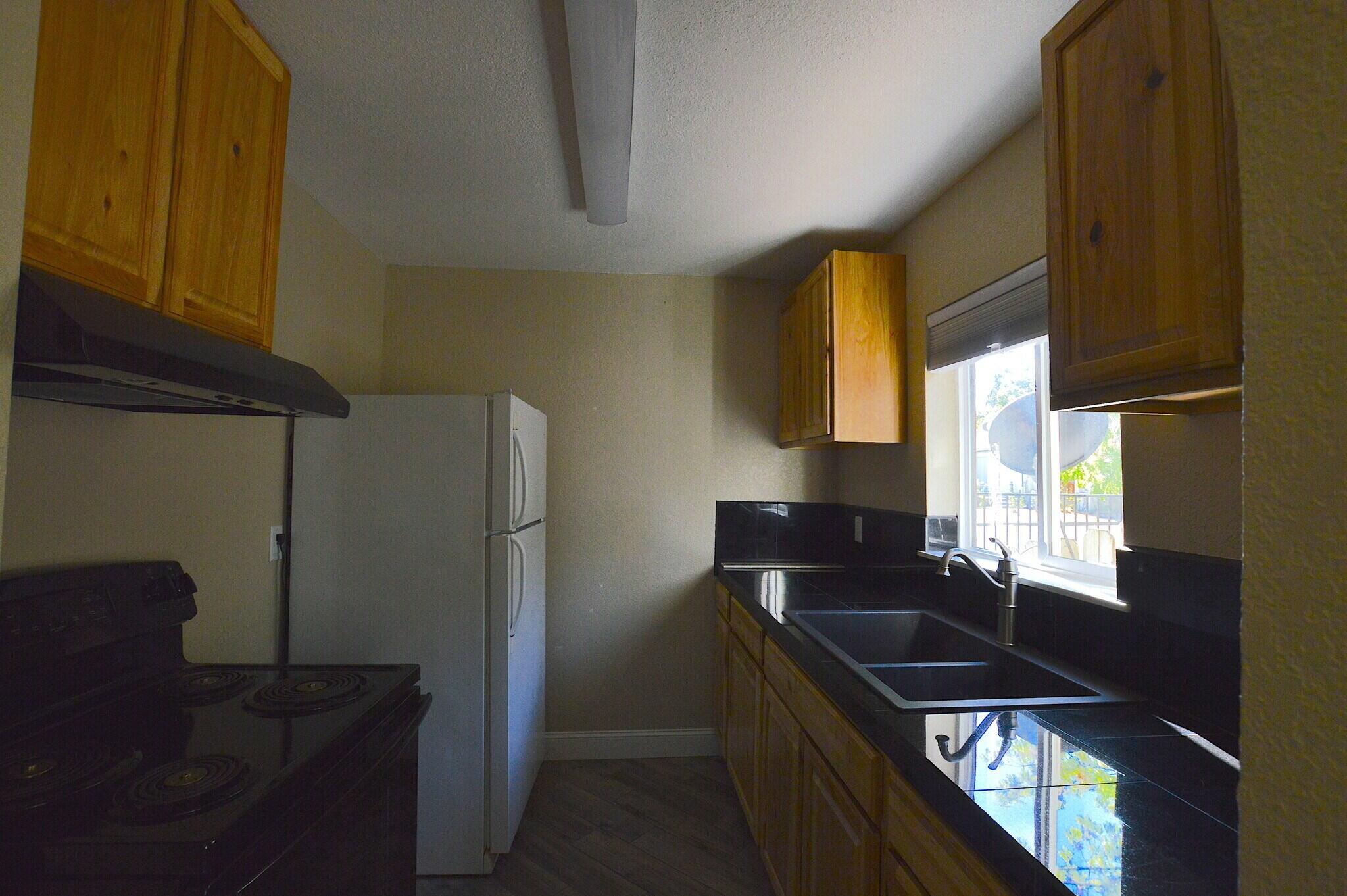 2230 El Reno Lane Redding, CA 96001 - Photo 15 of 27 a kitchen with granite countertop a refrigerator a stove a sink and a dining table with wooden floor