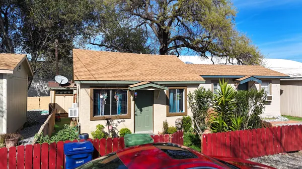 a front view of house with yard outdoor seating and trees in the background