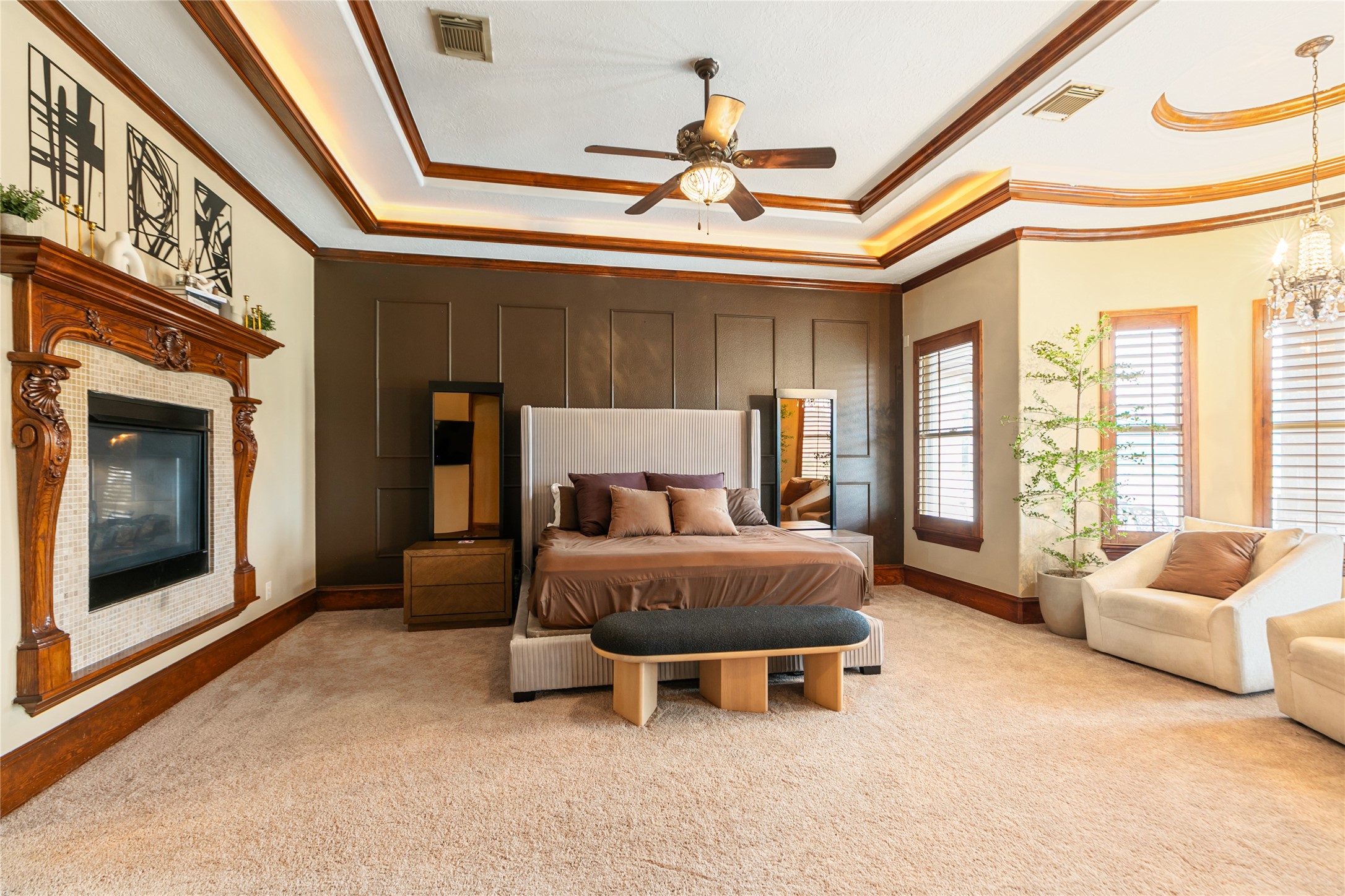 22 Post Shadow Estate Drive Spring, TX 77389 - Photo 34 of 50 The luxurious primary bedroom, highlighted by the fireplace, large windows, beautiful paneling, molding, and an elegant tray ceiling, creates a warm and inviting retreat for relaxation.