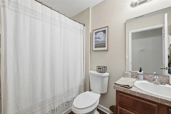 a bathroom with a granite countertop sink a toilet and a mirror