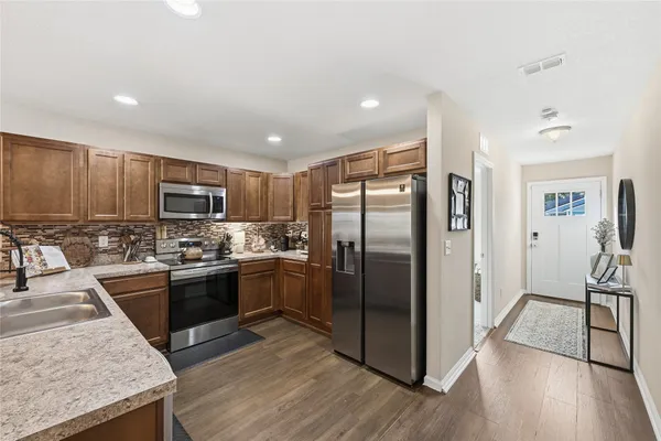 a kitchen with stainless steel appliances granite countertop a refrigerator a stove top oven a sink and dishwasher with wooden floor