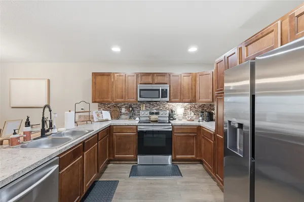 a kitchen with stainless steel appliances granite countertop a sink a stove a refrigerator and cabinets