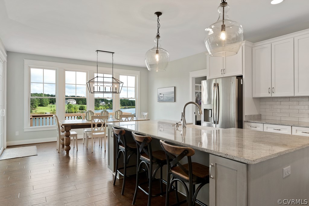 3812 Millmount Drive Powhatan, VA 23139 - Photo 15 of 48 an open kitchen with granite countertop a stove a refrigerator a sink a dining table and chairs with wooden floor