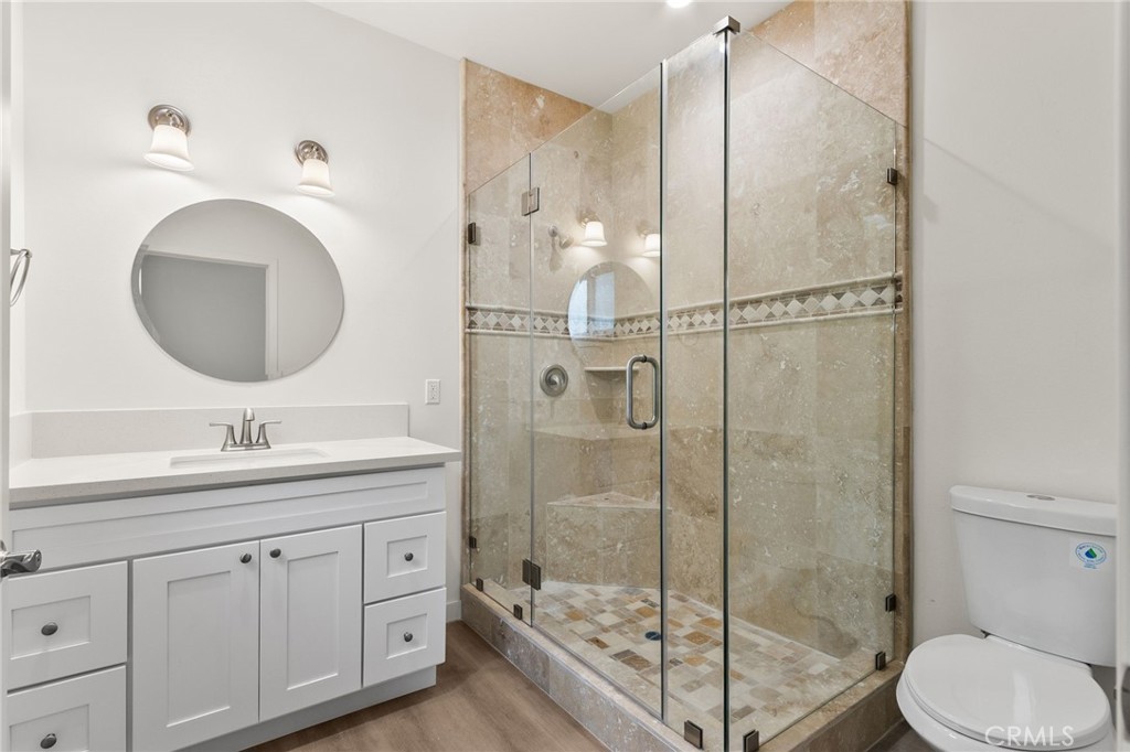 4508 Hedda Street, Unit 2 Lakewood, CA 90712 - Photo 9 of 10 a bathroom with a toilet a sink a glass door a shower and mirror