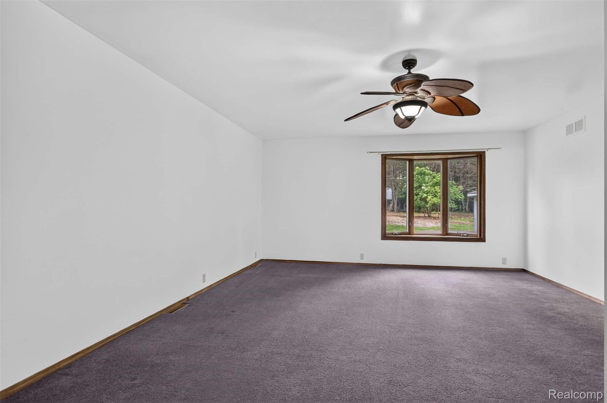 1437 East Cook Road Grand Blanc, MI 48439 - Photo 53 of 69 Spacious interior featuring a large bay window, ceiling fan with integrated lighting, and dark grey carpeting