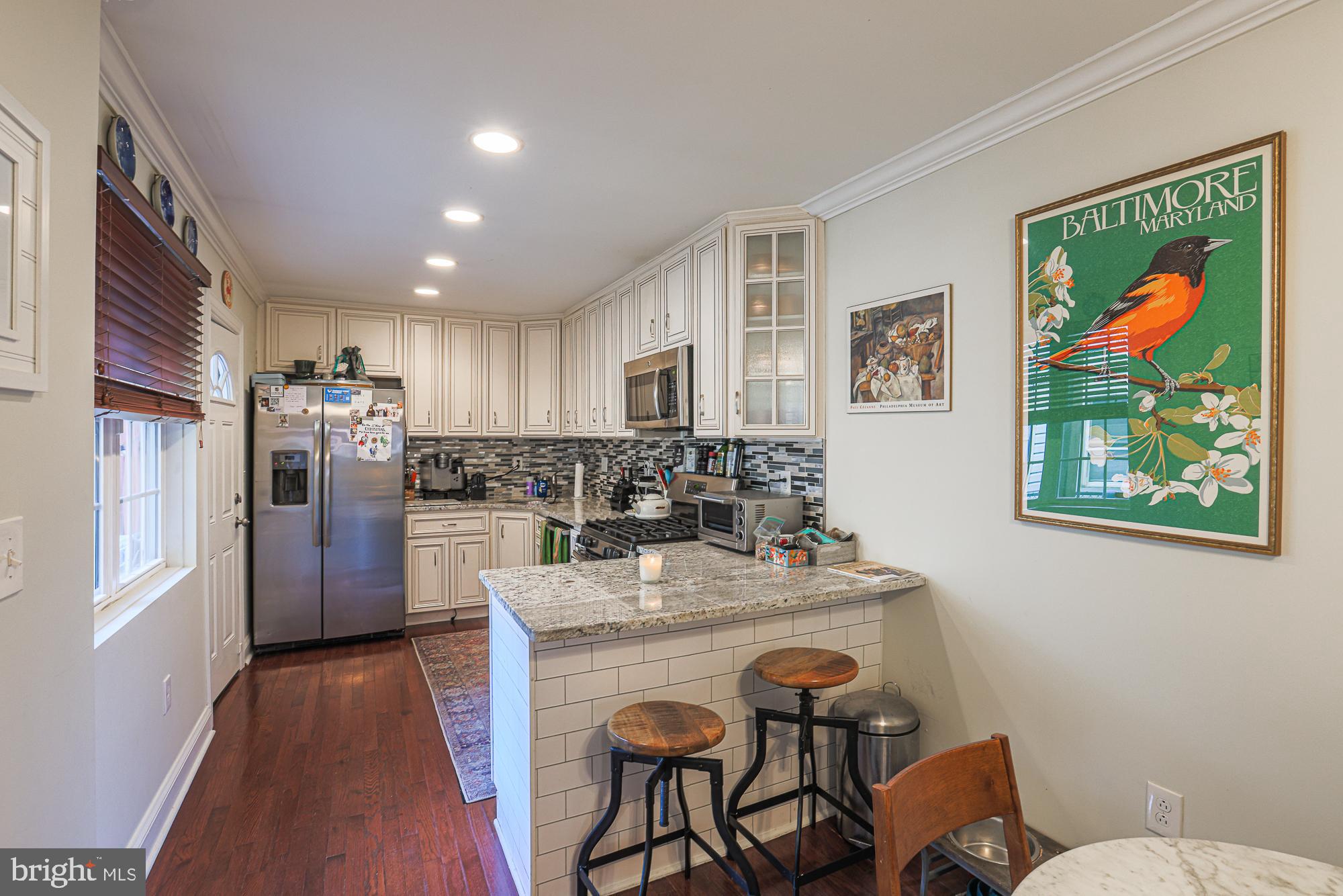 1446 Hull Street Baltimore, MD 21230 - Photo 16 of 54 a kitchen with stainless steel appliances granite countertop a refrigerator a stove a sink a dining table and chairs with wooden floor