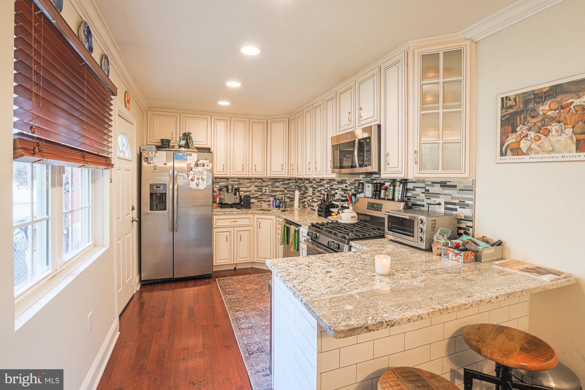 1446 Hull Street Baltimore, MD 21230 - Photo 17 of 54 a kitchen with stainless steel appliances kitchen island granite countertop a refrigerator a stove and a sink with wooden floor