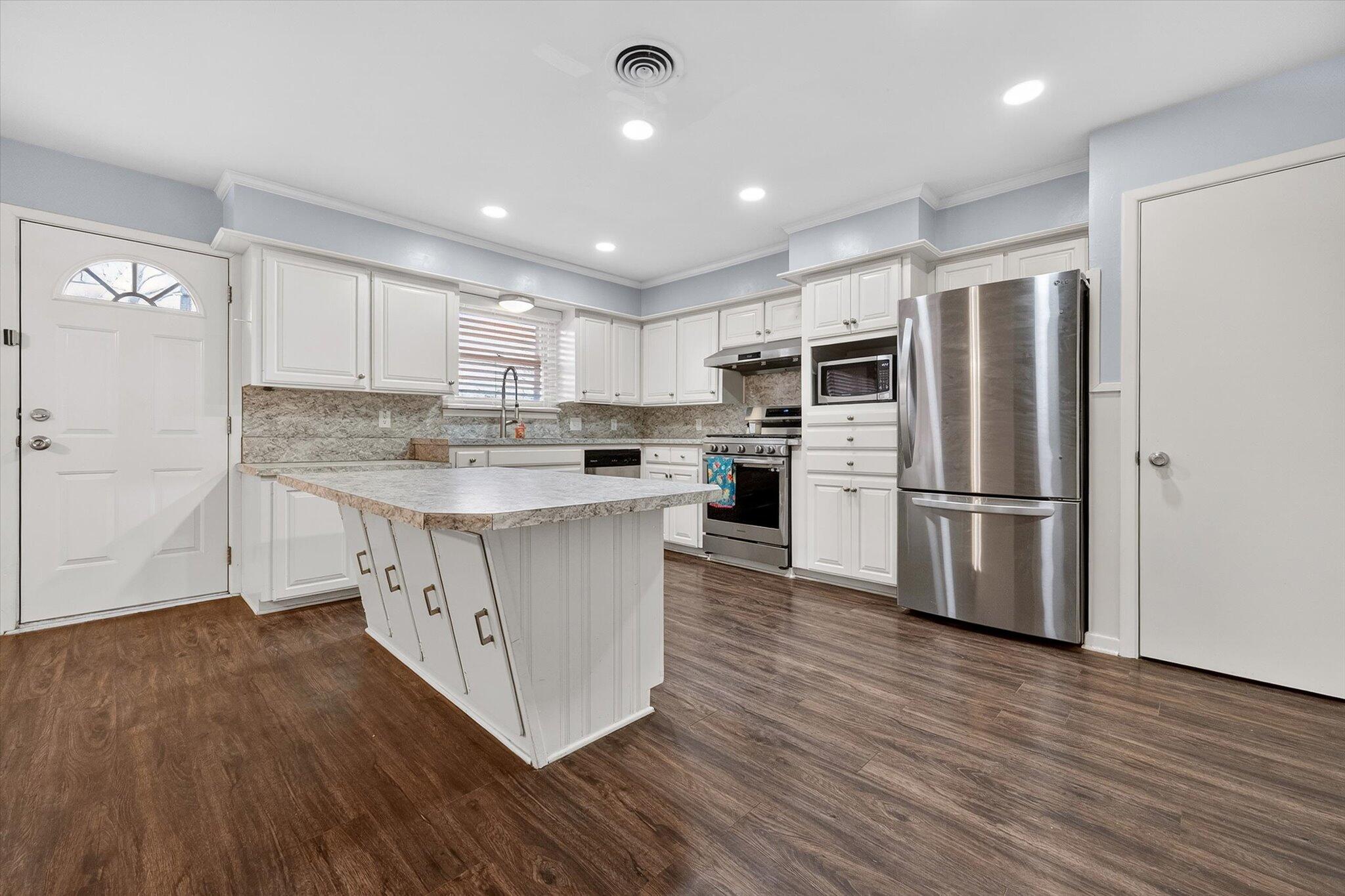 4915 17th Street Lubbock, TX 79416 - Photo 13 of 29 a kitchen with kitchen island a sink a stove a refrigerator cabinets and a center island