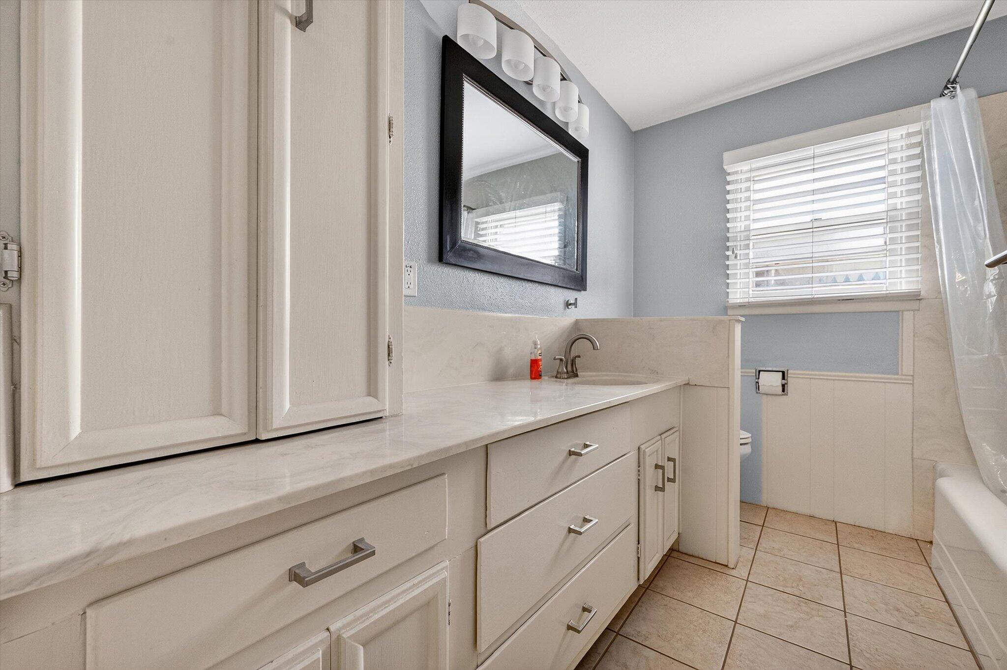 4915 17th Street Lubbock, TX 79416 - Photo 8 of 29 a bathroom with a sink and a mirror