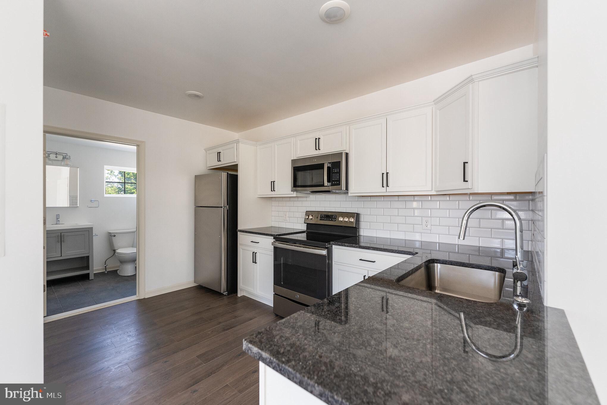 a kitchen with stainless steel appliances granite countertop a sink stove microwave and refrigerator