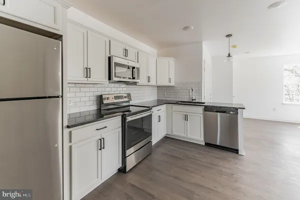 a white kitchen with granite countertop stainless steel appliances