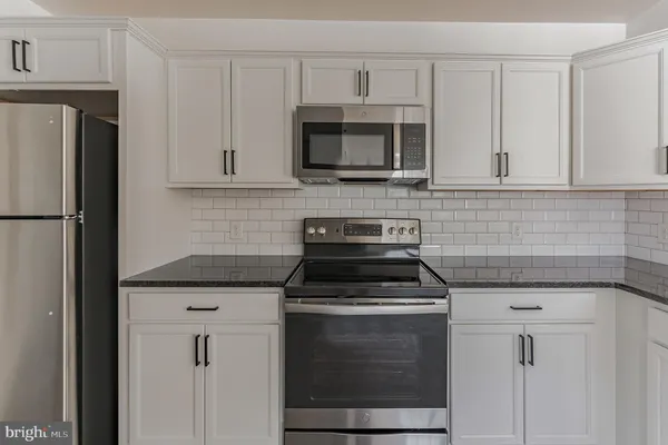 a kitchen with white cabinets and stainless steel appliances
