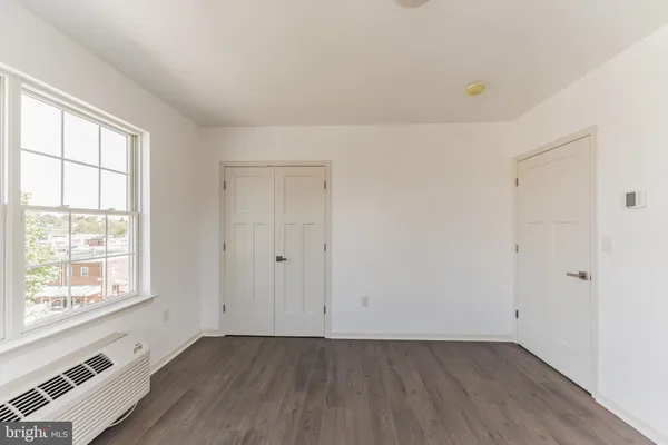 an empty room with wooden floor and windows