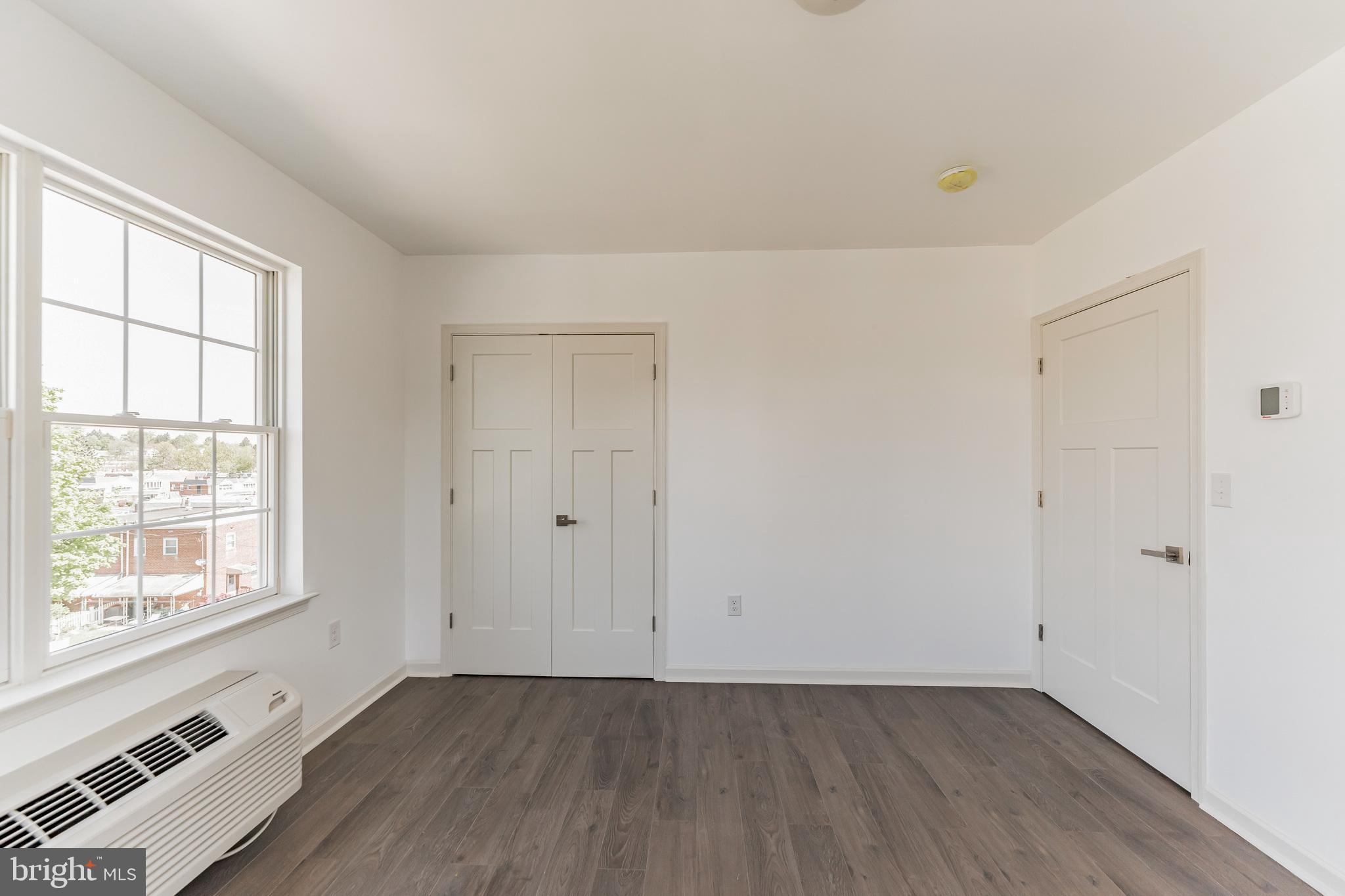 7105 Ridge Avenue, Unit A3 Philadelphia, PA 19128 - Photo 6 of 10 an empty room with wooden floor and windows