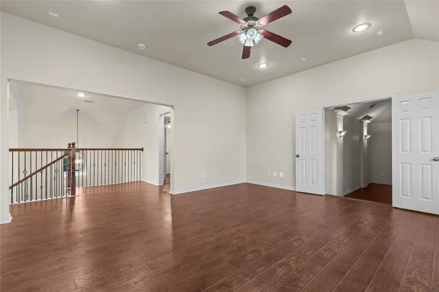 an empty room with wooden floor and fan