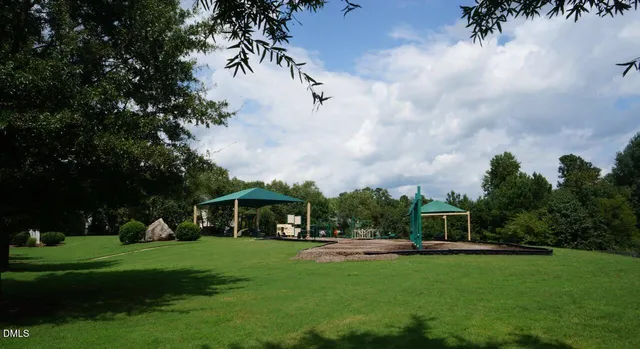 a view of a park with table and chairs potted plants and big trees