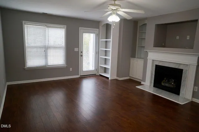a view of a livingroom with wooden floor a fireplace and window