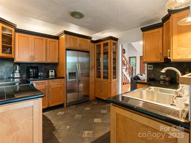 a kitchen with stainless steel appliances granite countertop a refrigerator a stove and a sink with wooden cabinets