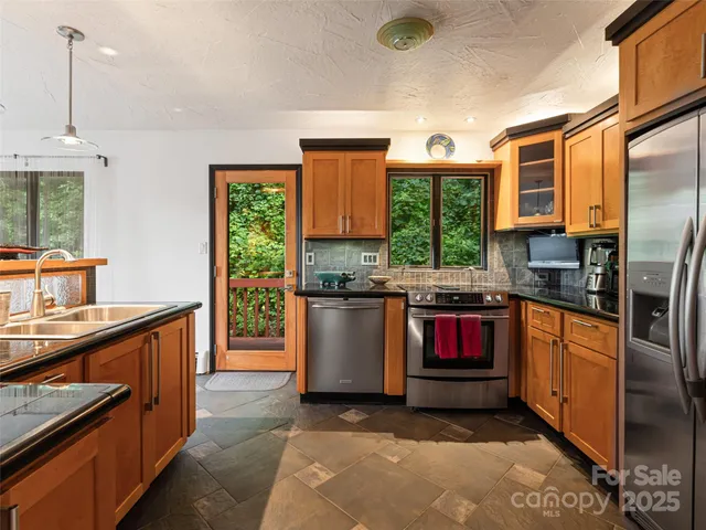 a kitchen with stainless steel appliances granite countertop a stove a sink and a microwave