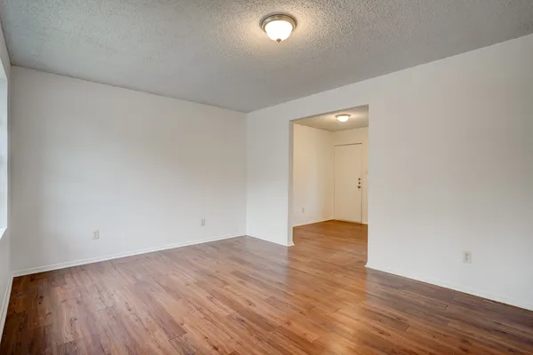 a view of an empty room with wooden floor and closet