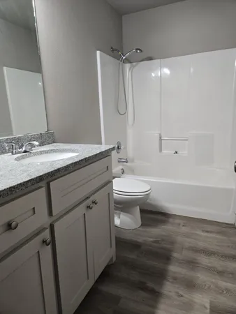 a bathroom with a granite countertop sink toilet a mirror and shower
