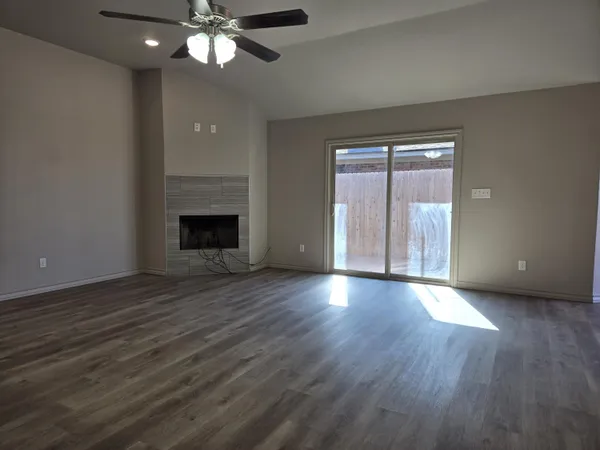 a view of an empty room with wooden floor and a fireplace