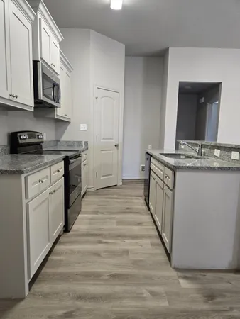 a kitchen with stainless steel appliances granite countertop a stove top oven a sink dishwasher and a microwave oven with large wooden cabinets