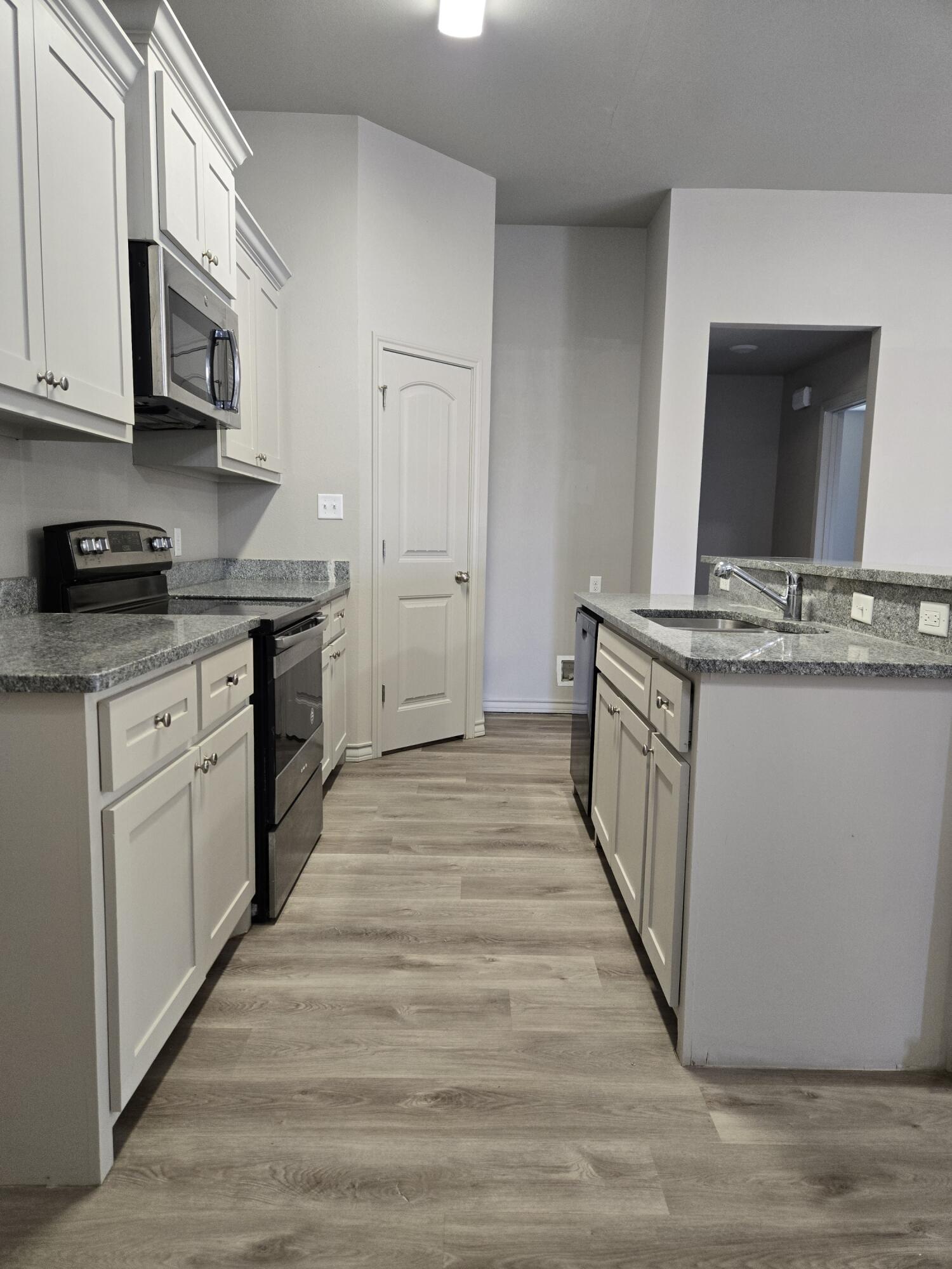 2709 County Road 7700 Lubbock, TX 79423 - Photo 9 of 29 a kitchen with stainless steel appliances granite countertop a stove top oven a sink dishwasher and a microwave oven with large wooden cabinets
