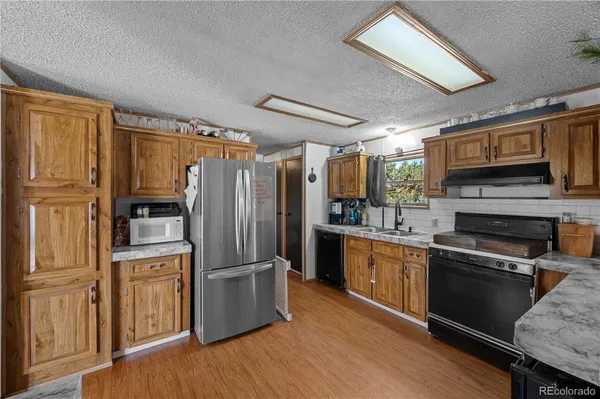 a kitchen with stainless steel appliances granite countertop a refrigerator oven a sink dishwasher and wooden cabinets with wooden floor