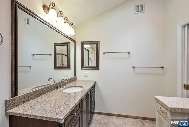 a bathroom with a granite countertop sink and a mirror