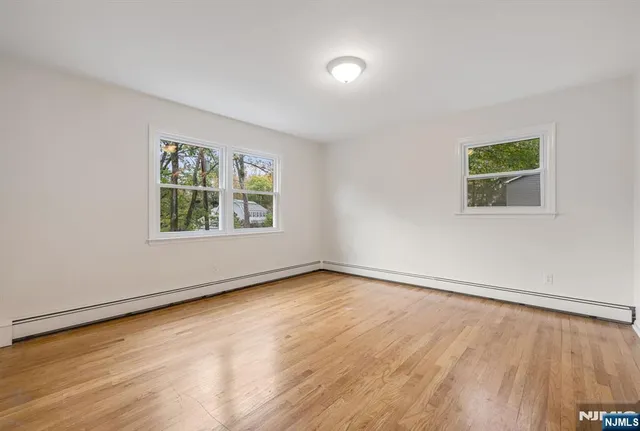 an empty room with wooden floor and window