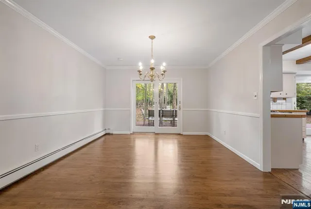 an empty room with wooden floor chandelier and windows