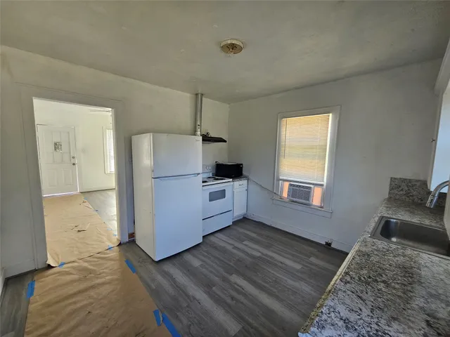 a kitchen with a refrigerator and wooden floor