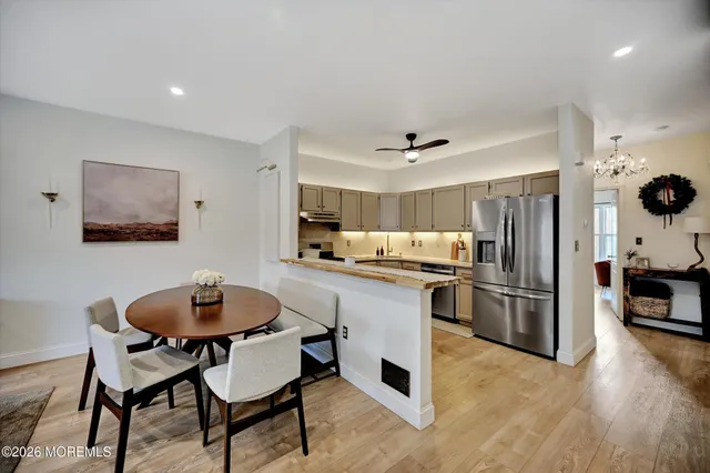 a kitchen with stainless steel appliances kitchen island granite countertop a table chairs and a refrigerator