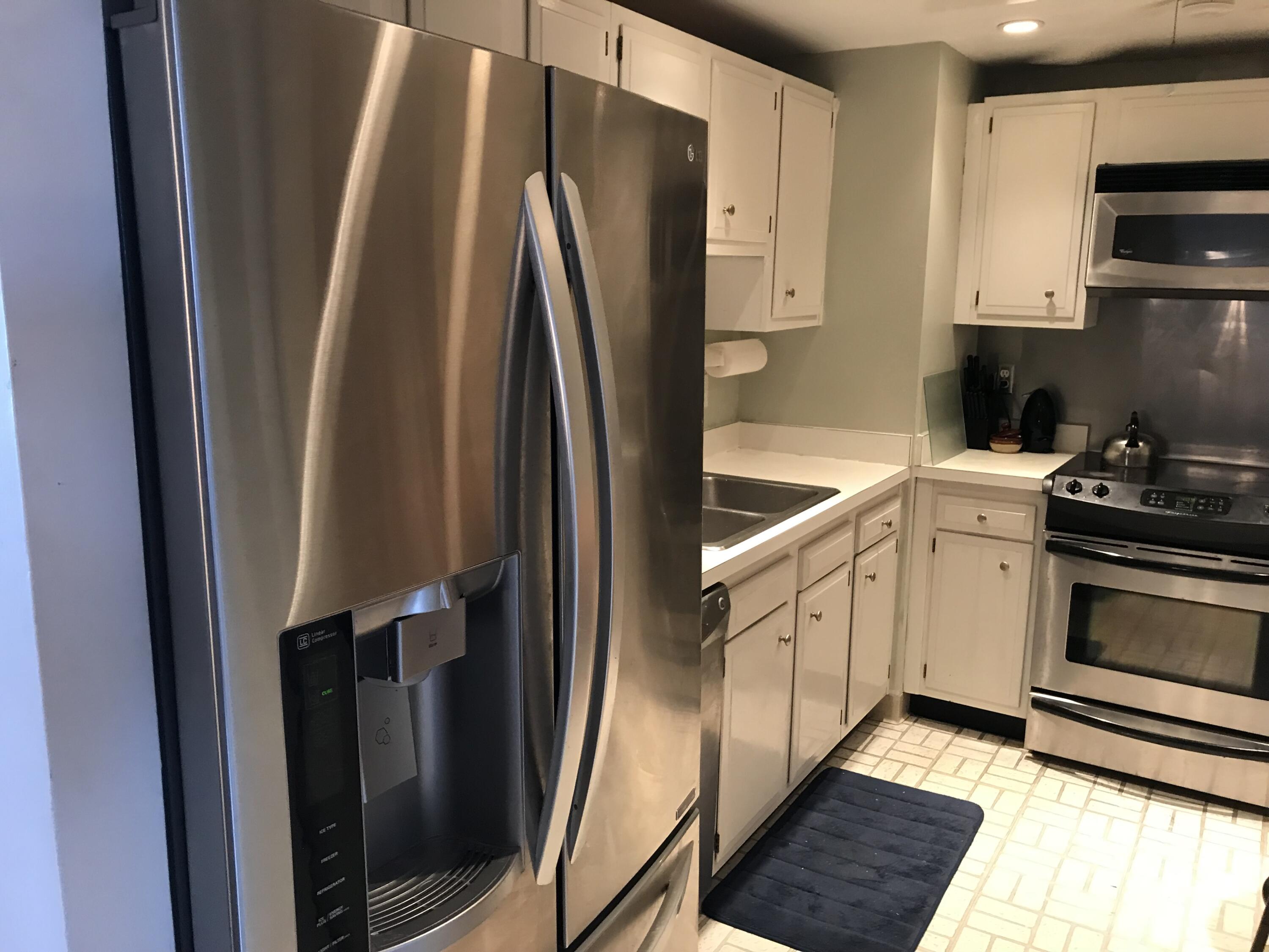 5200 North Flagler Drive, Unit 702 West Palm Beach, FL 33407 - Photo 30 of 36 a kitchen with white cabinets and stainless steel appliances