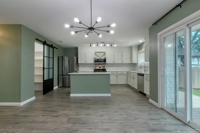 a kitchen with stainless steel appliances kitchen island granite countertop a refrigerator a stove top oven a sink and dishwasher