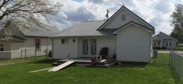 a front view of a house with a garden and chairs