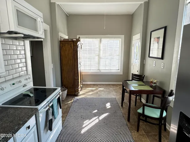 a kitchen that has a sink a stove and chair
