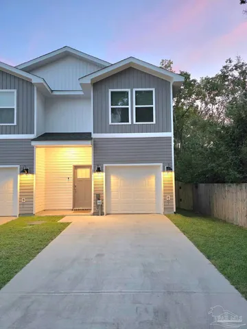 a view of a house with a yard and a large tree