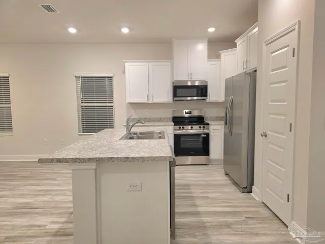 a kitchen with stainless steel appliances granite countertop a refrigerator a stove and a sink