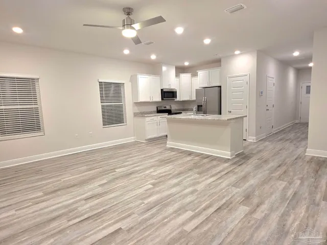 a view of a kitchen with kitchen island a sink wooden floor and a large window