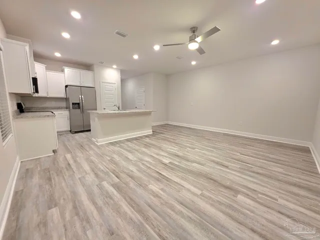 a view of a kitchen with kitchen island a sink wooden floor and stainless steel appliances