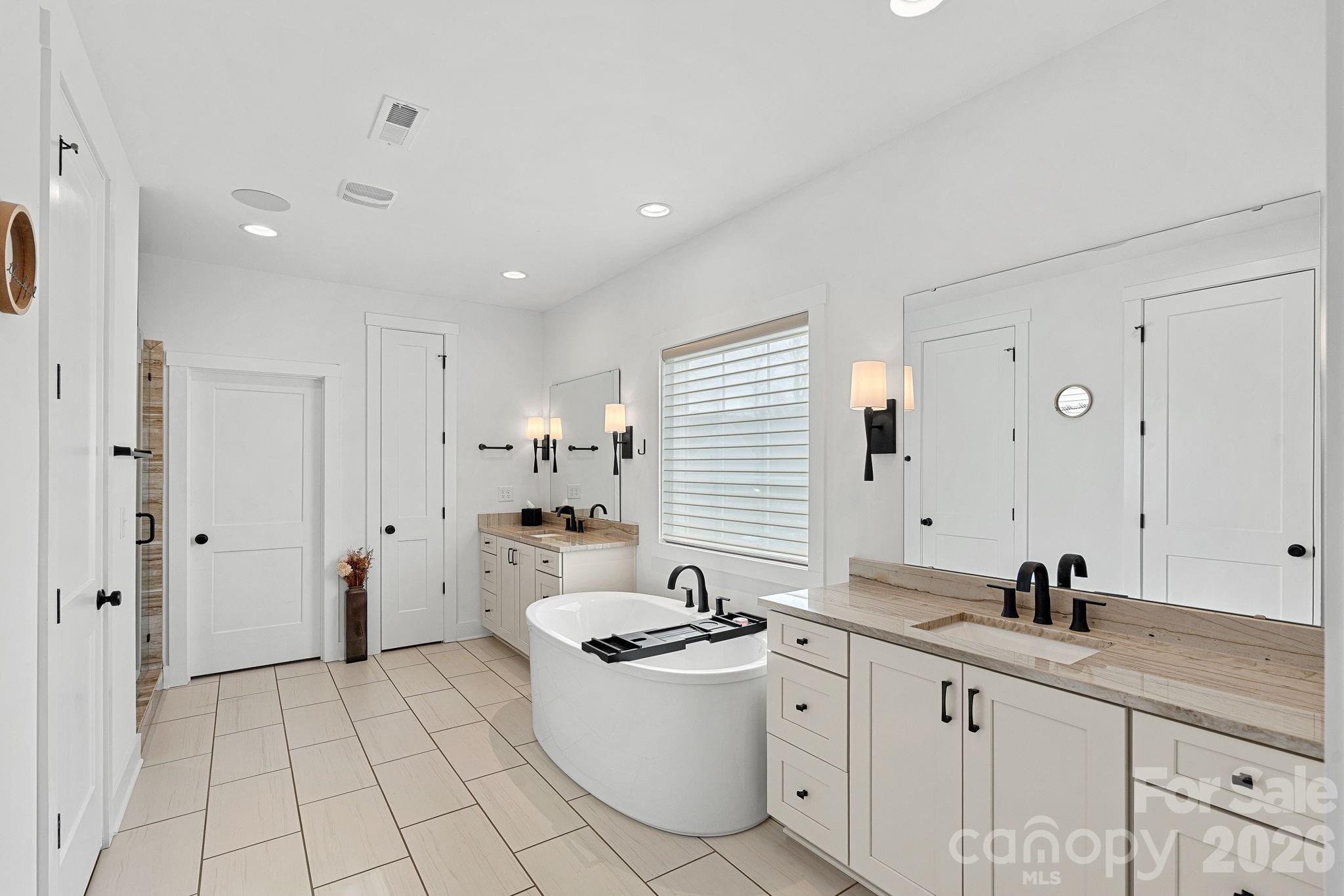 18401 Doves Crest Road Cornelius, NC 28031 - Photo 32 of 39 a spacious bathroom with a granite countertop sink a toilet a mirror and a bathtub