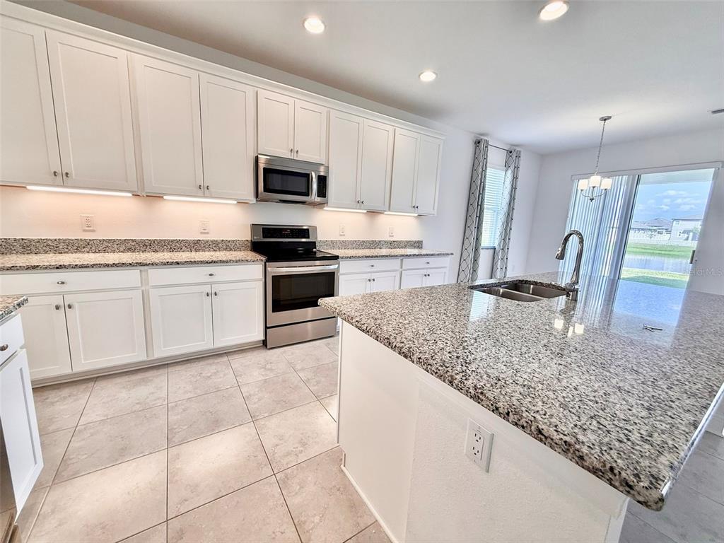 12189 Nouveau Avenue Spring Hill, FL 34610 - Photo 15 of 50 a kitchen with stainless steel appliances granite countertop a sink stove and cabinets
