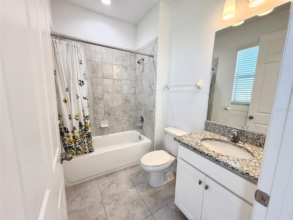 12189 Nouveau Avenue Spring Hill, FL 34610 - Photo 22 of 50 a bathroom with a granite countertop sink a toilet a mirror a bathtub and shower