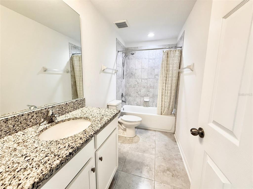 12189 Nouveau Avenue Spring Hill, FL 34610 - Photo 33 of 50 a bathroom with a granite countertop sink toilet and shower