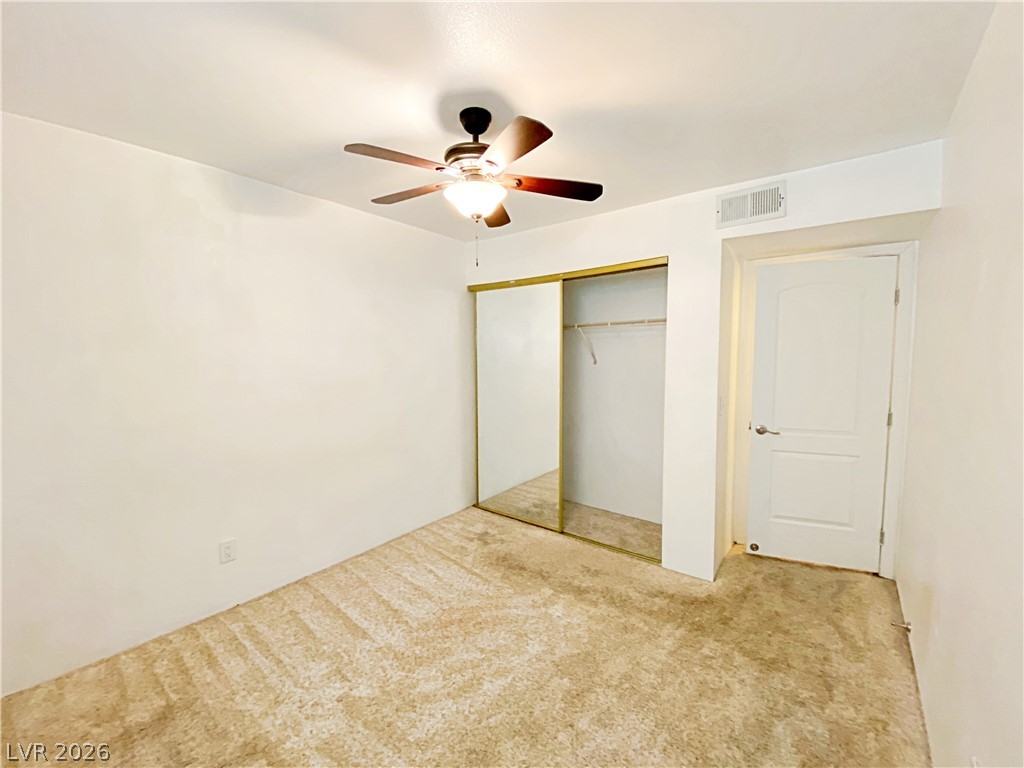 3145 East Flamingo Road, Unit 1128 Las Vegas, NV 89121 - Photo 10 of 19 A well-lit bedroom features practical mirrored closet doors and a ceiling fan for comfort.