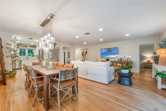a view of a dining room and livingroom with furniture wooden floor a chandelier