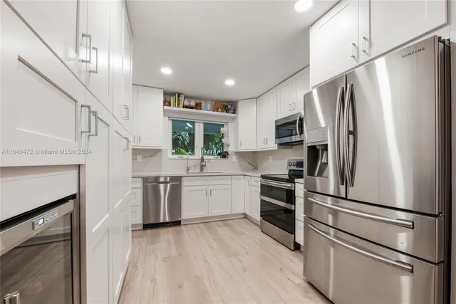 a kitchen with a refrigerator stainless steel appliances wooden floor and cabinets