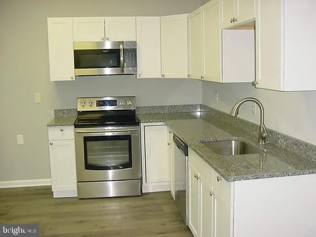 a kitchen with granite countertop a sink and a stove top oven